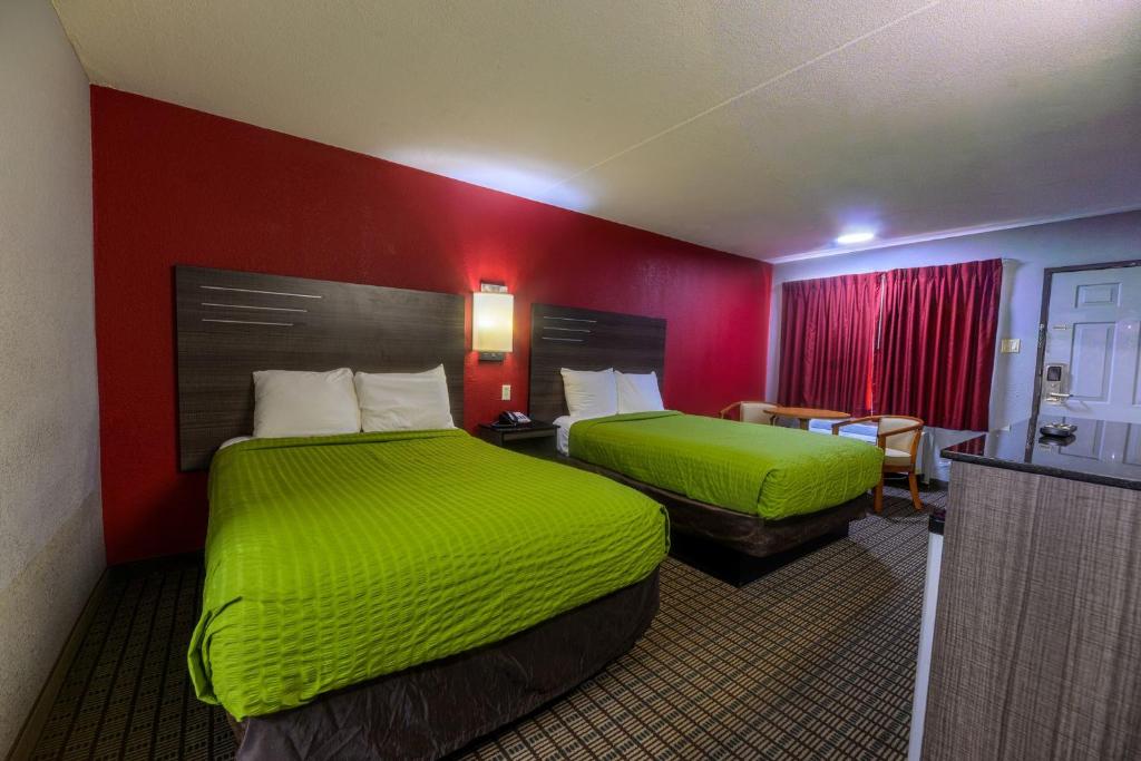 a hotel room with two beds with green sheets at The Lodge at the Falls in Wichita Falls
