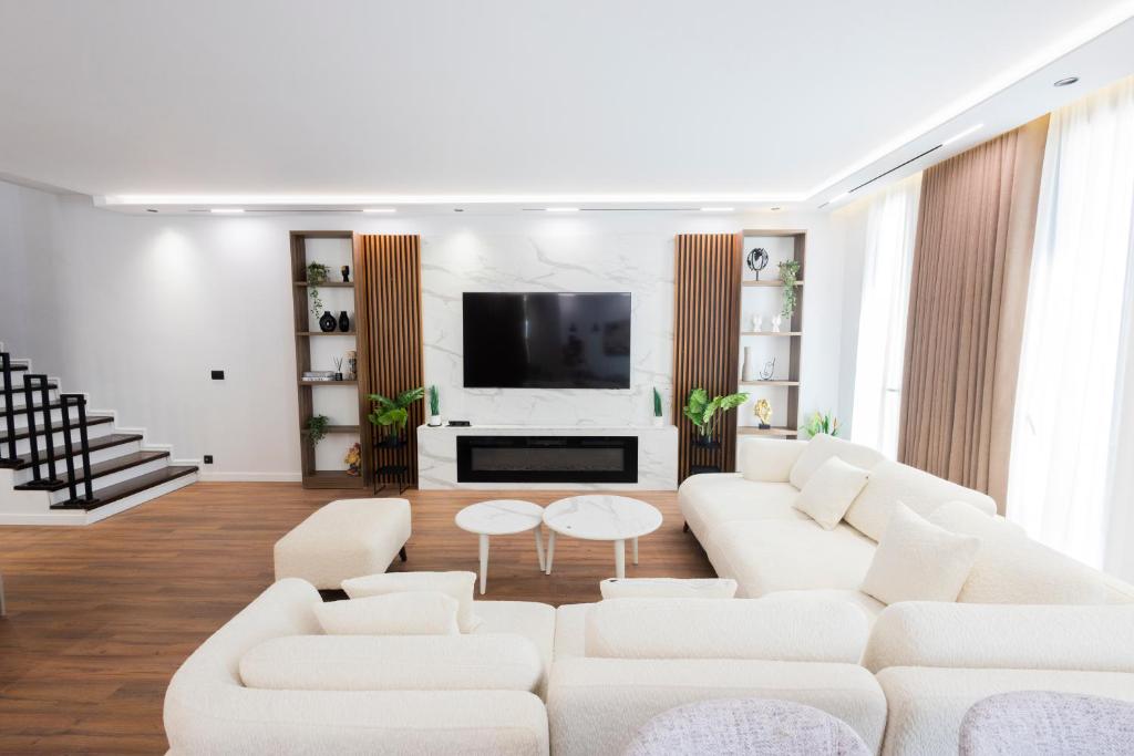 a living room with white furniture and a flat screen tv at Aria Luxury Villa 2 in Dhërmi