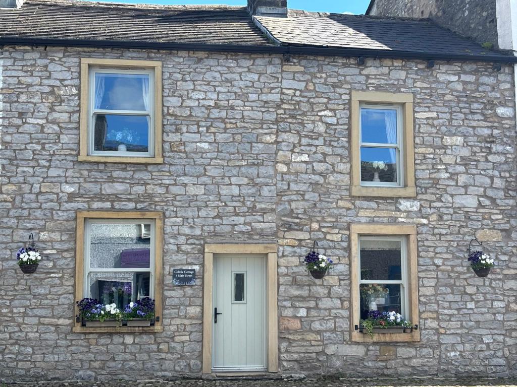 a stone house with a white door and windows at Cobble Cottage in Clitheroe