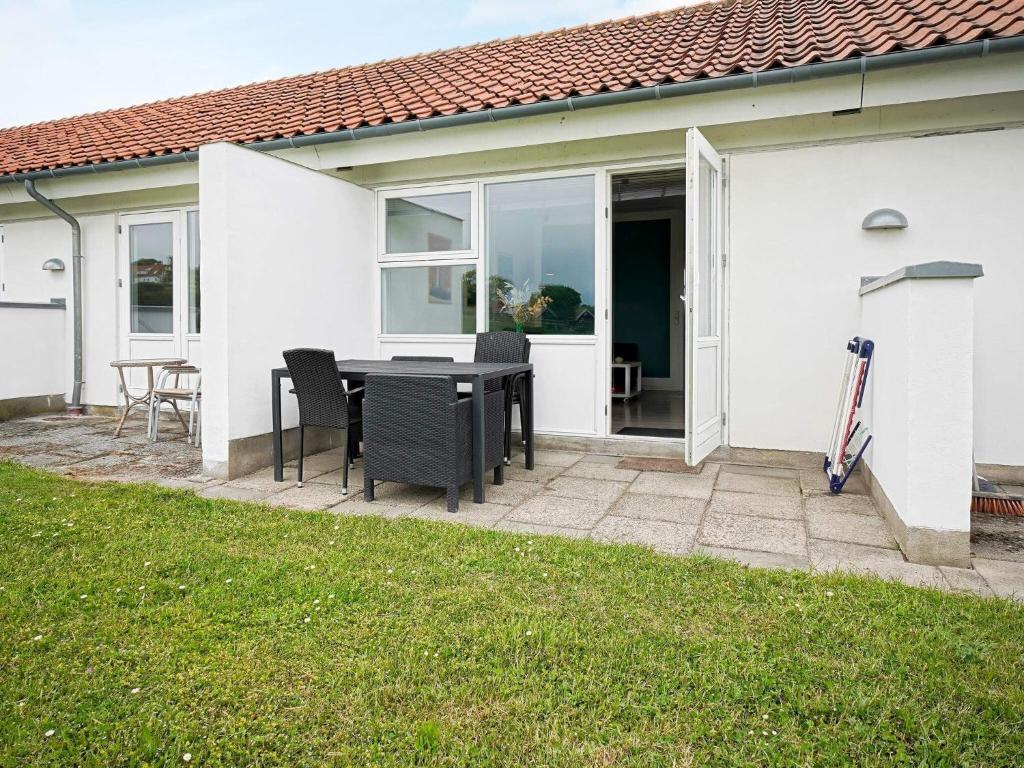 a patio with a table and chairs in front of a house at Seaside Property in Sandkas in Allinge