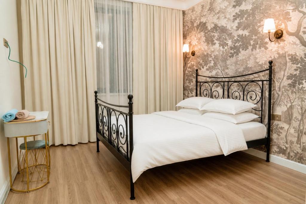 a bedroom with a black bed with white pillows at Sapphire Residence in Khujand