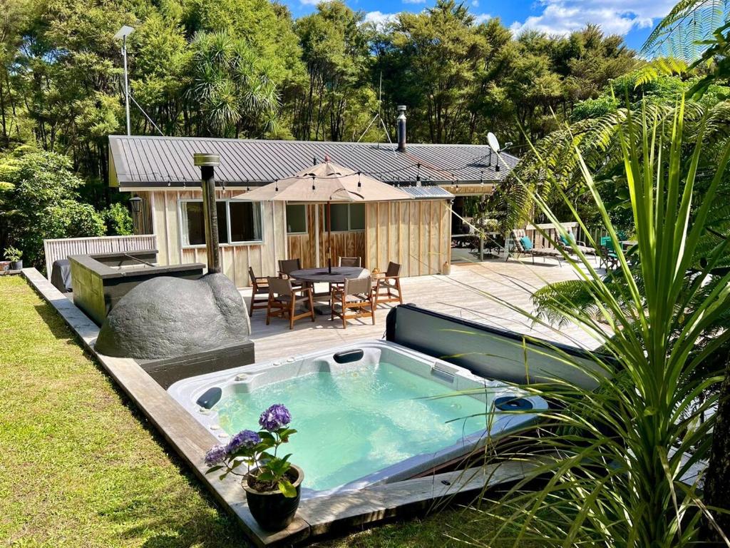 a hot tub in the yard of a house at Secluded Bush Retreat in Hikuai