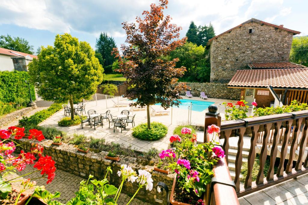 a woman standing on a balcony looking out at a garden at Hôtel Restaurant Au Pont de Raffiny in Saint-Romain