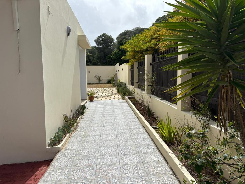a walkway with a white building and a fence at Villa cornich in Banzart