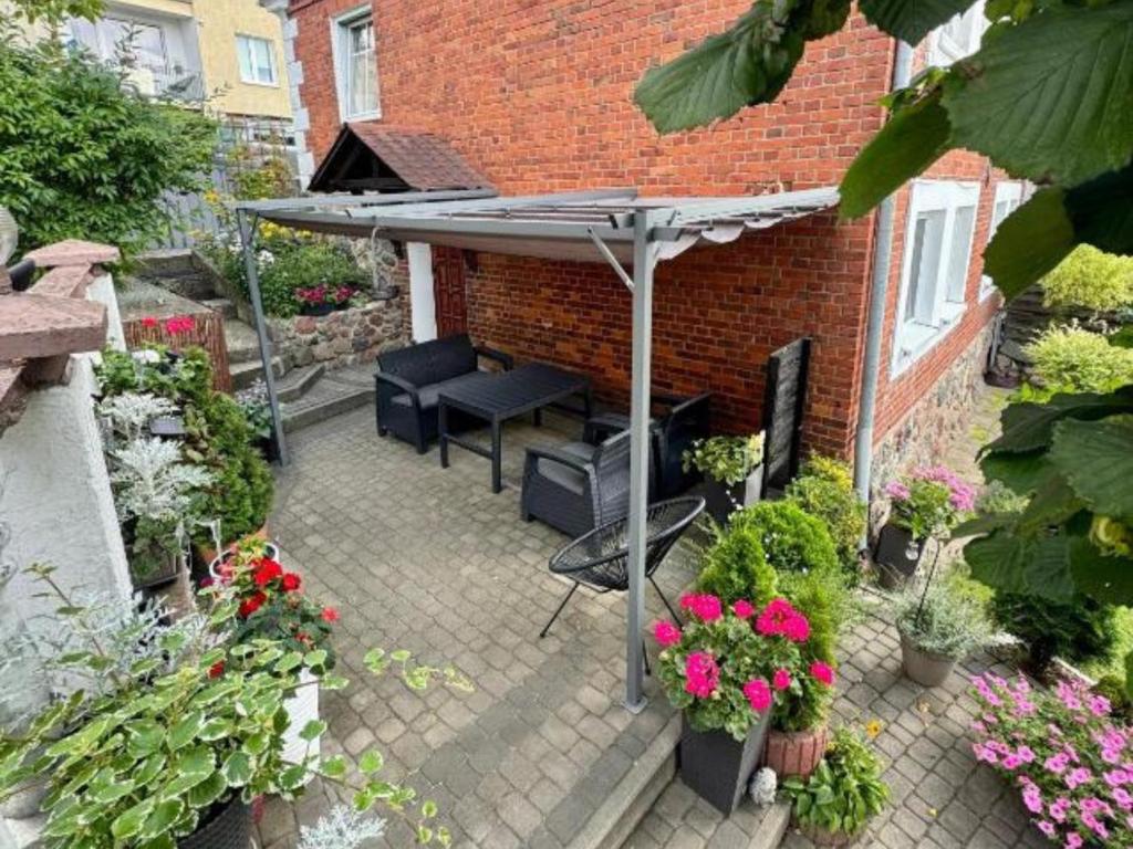 a patio with an umbrella and chairs and flowers at Apartament OLTO Mikołajki in Mikołajki