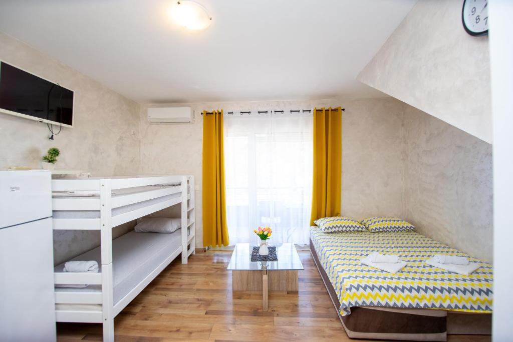 a bedroom with a bunk bed and yellow curtains at Apartmani Čukić Rafailovići in Budva
