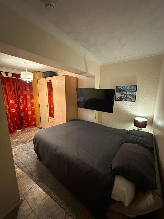 a bedroom with a large bed and a flat screen tv at Heathrow Ensuite in West Drayton