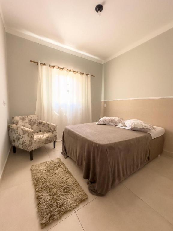 a bedroom with a bed and a chair at Casa Doce Lar 2 in Uberaba