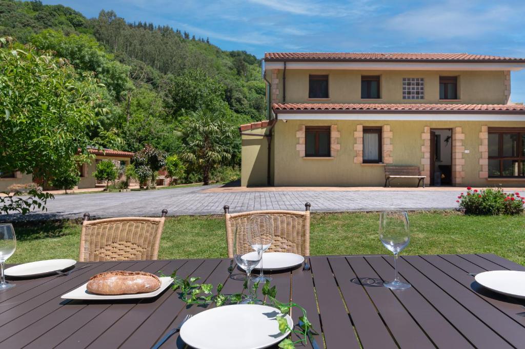 a wooden table with a plate of food and a house at NorthStyle by Fidalsa in Lanestosa