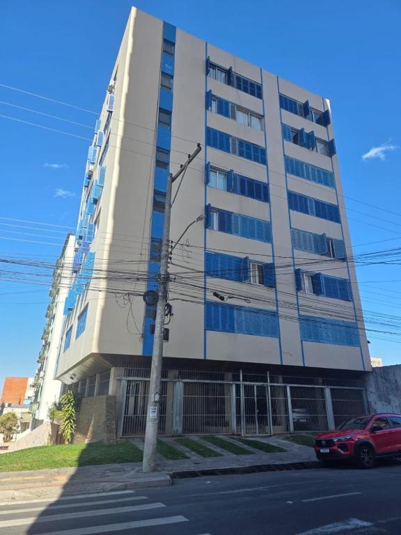 a tall building with a red car parked in front of it at Ap Central 3 quartos com elevador e garagem in Pelotas