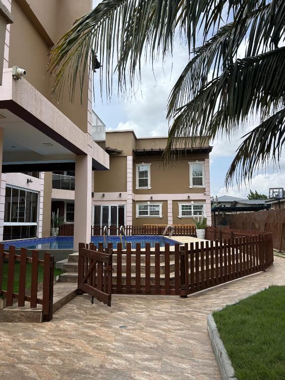 a house with a fence and a swimming pool at Villa Char in Accra
