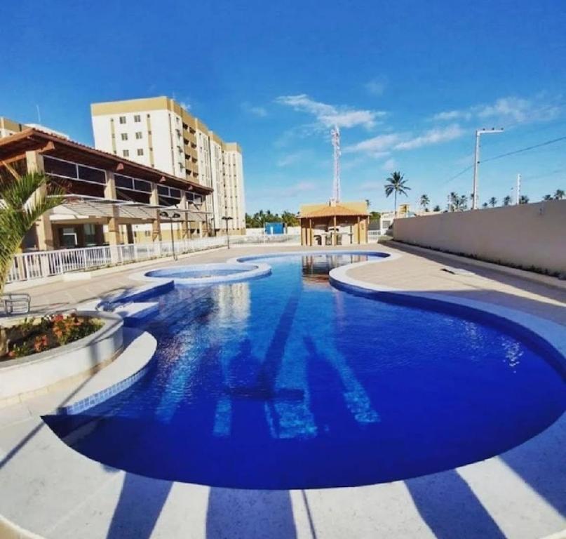 a large pool with blue water in a building at Horto da Barra - Apartamento à Beira Mar in Barra dos Coqueiros