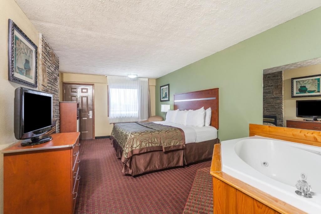 a hotel room with a bed and a bath tub at Baymont by Wyndham Pigeon Forge near Island Drive in Pigeon Forge