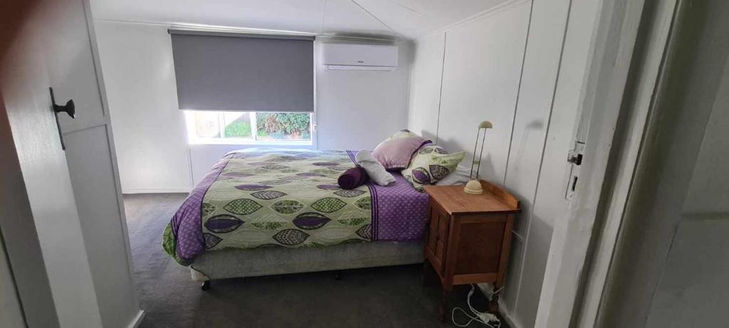 a bedroom with a bed and a table and a window at Mimis Cottage in Cohuna