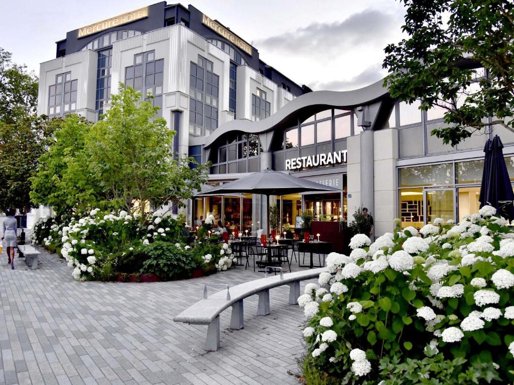 a building with benches and flowers in front of it at Mercure Nantes Centre Gare in Nantes
