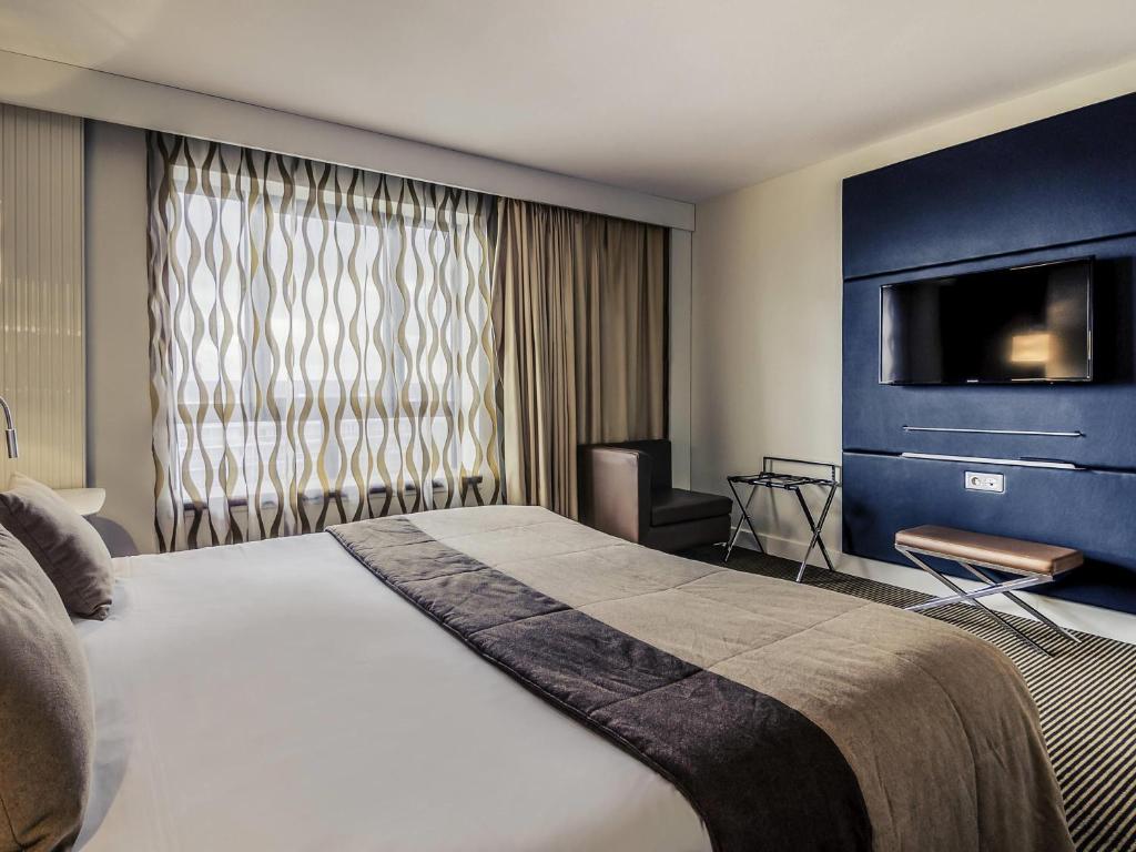 a hotel room with a bed and a tv at Mercure Cergy Pontoise Centre in Cergy