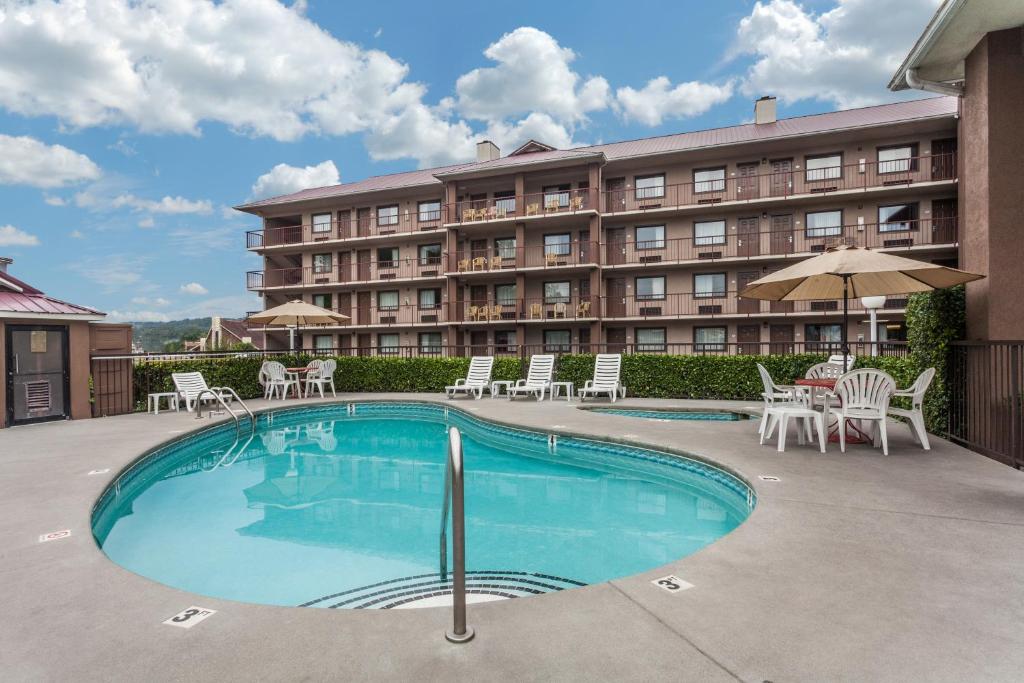a hotel with a swimming pool and chairs and a building at Baymont by Wyndham Pigeon Forge near Island Drive in Pigeon Forge