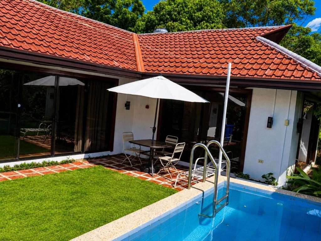 a patio with a table and an umbrella next to a house at Villa Flora Bella Yellow Bell in Dauis