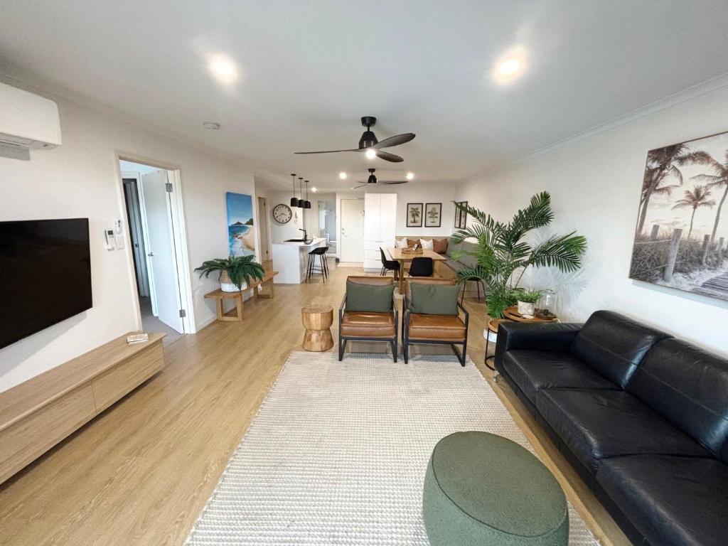 a living room with a black leather couch and a dining room at Jubilee Apartment 05 - Bring your own linen in South West Rocks
