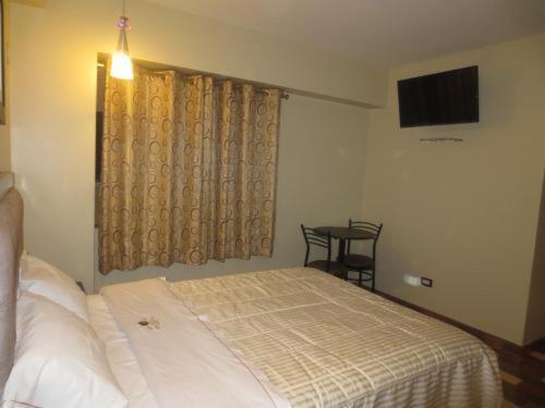 a bedroom with a bed and a table and a television at Hospedaje con recojo in Lima