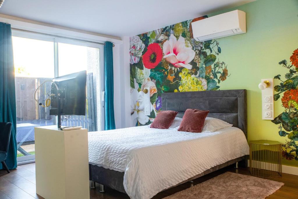a bedroom with a bed with a floral wall at Suite Touraco, clim, balneo, terrasse - Parc des Oiseaux in Villars-les-Dombes