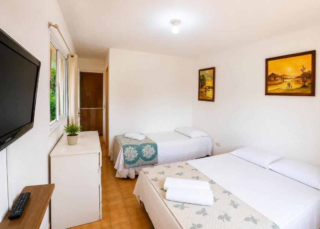 a small room with two beds and a television at Suites Mar a Vista in Porto De Galinhas