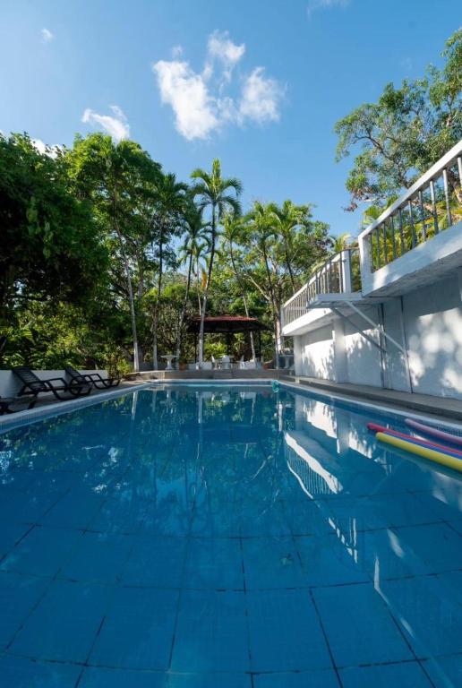 a swimming pool with a building and trees at Las cabañas in Jacó
