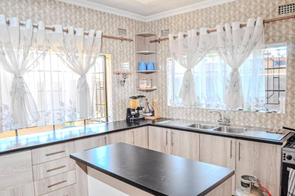 a kitchen with a sink and two windows at Victoria Falls Accomodation in Victoria Falls