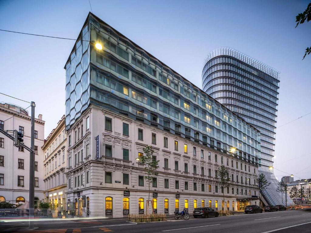 a tall building on a city street with a building at Novotel Wien City in Vienna