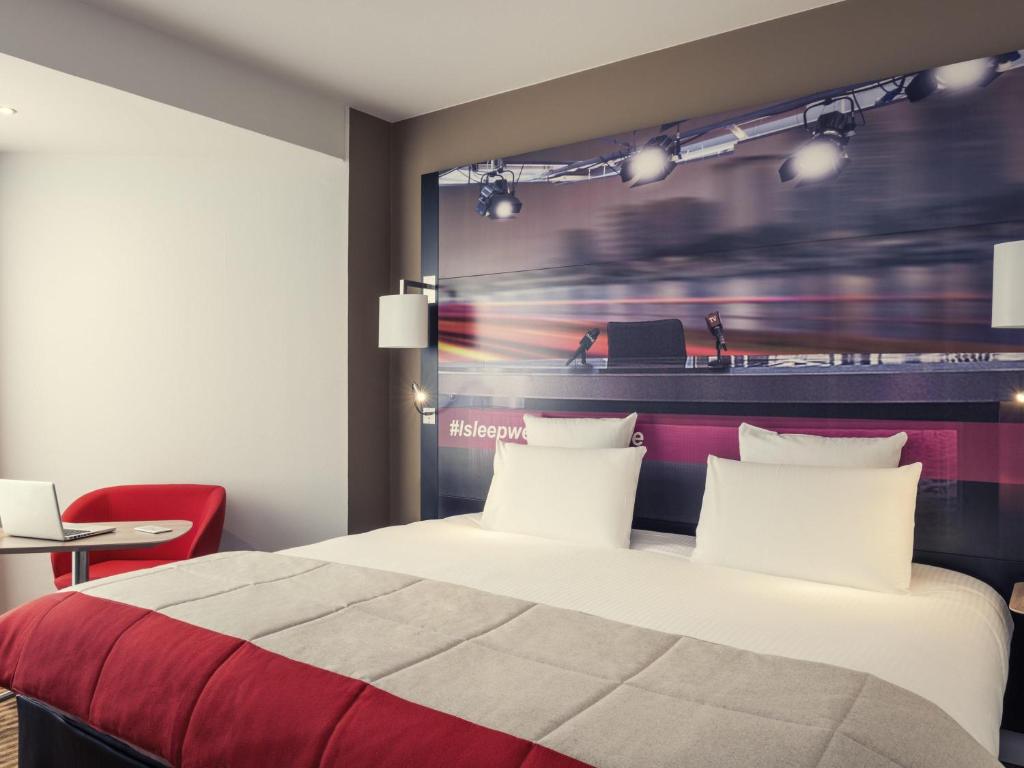 a bedroom with a bed with a red and white blanket at Mercure Paris Boulogne in Boulogne-Billancourt