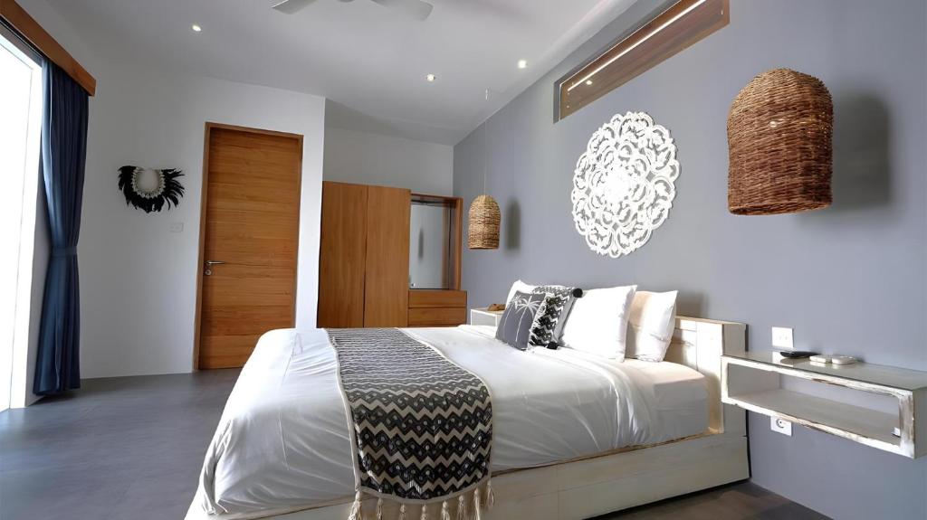 a bedroom with a large bed with white sheets and pillows at Villa Sarn 1 Sanur in Sanur