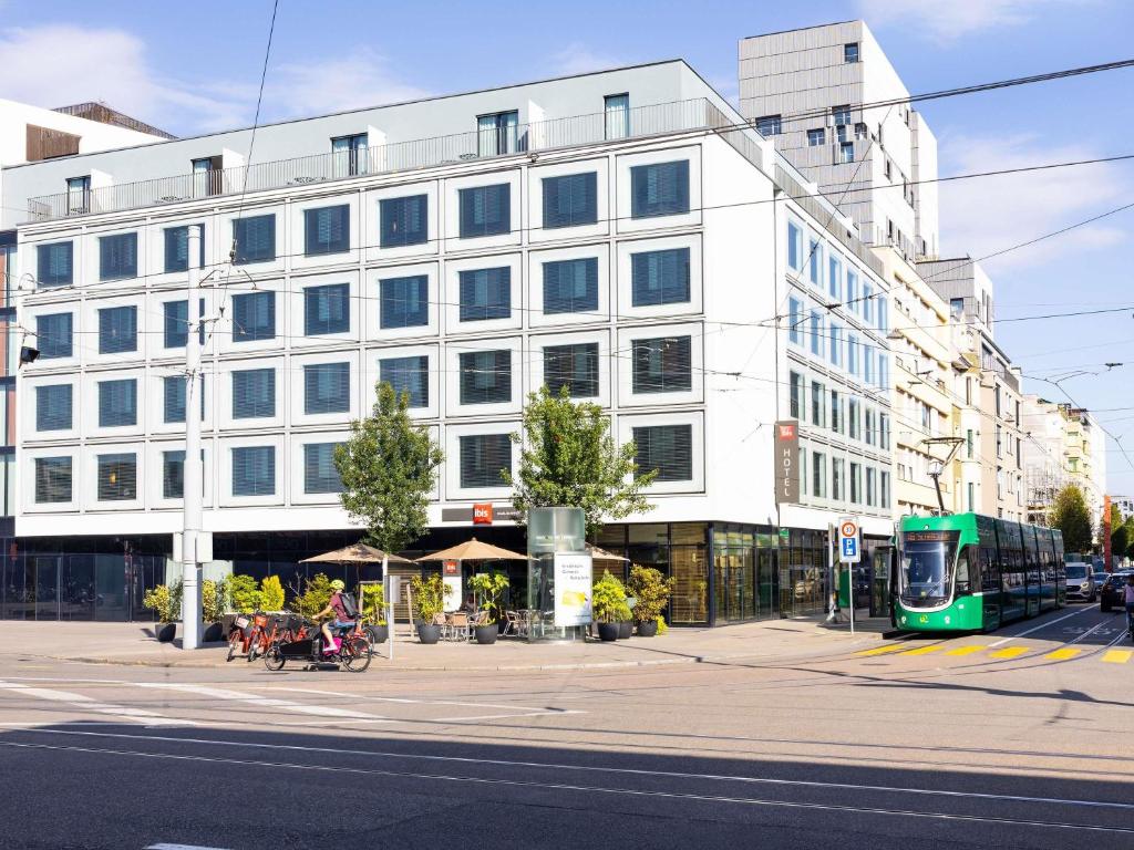 a large white building on a city street with a bus at ibis Basel Bahnhof in Basel