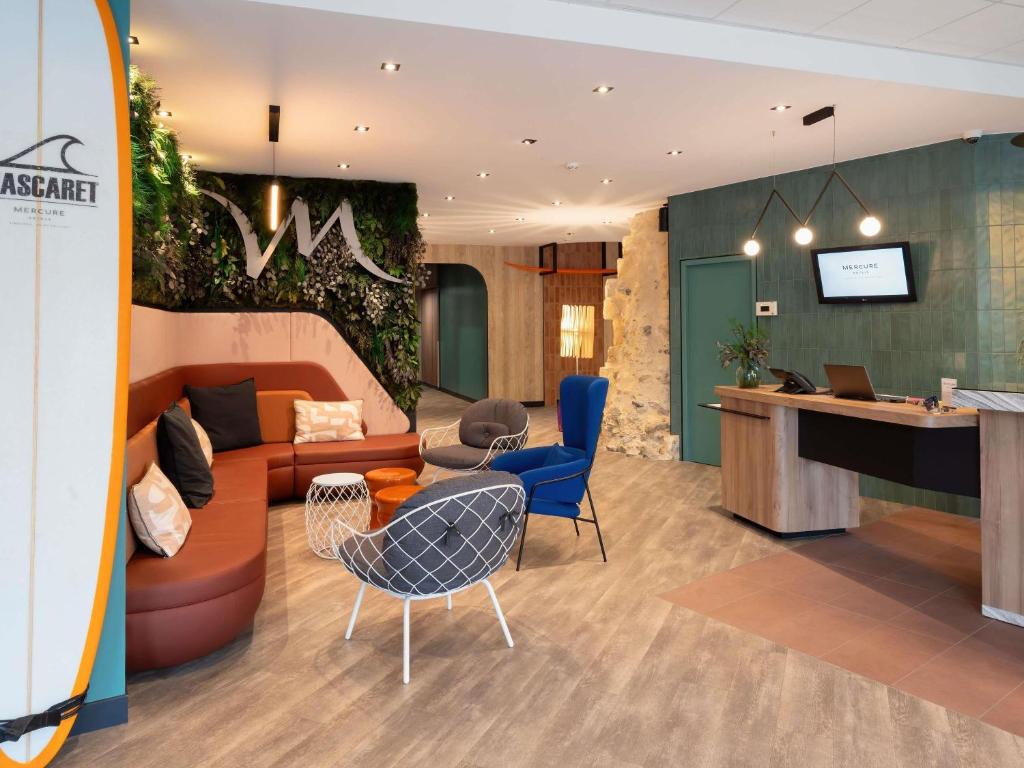 an office lobby with a couch and chairs and a desk at Mercure Libourne Saint Emilion in Libourne