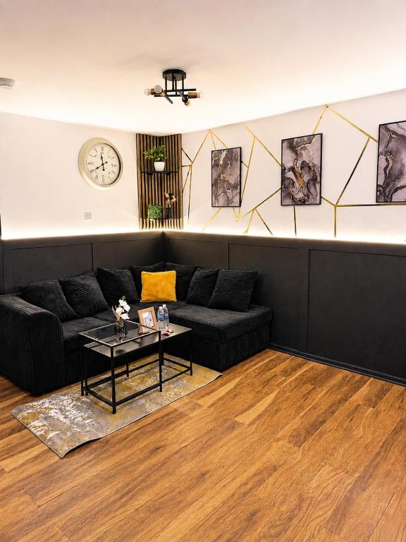 a living room with a black couch and a clock at House in Manchester MVS Snug Urban Hideaway in Manchester