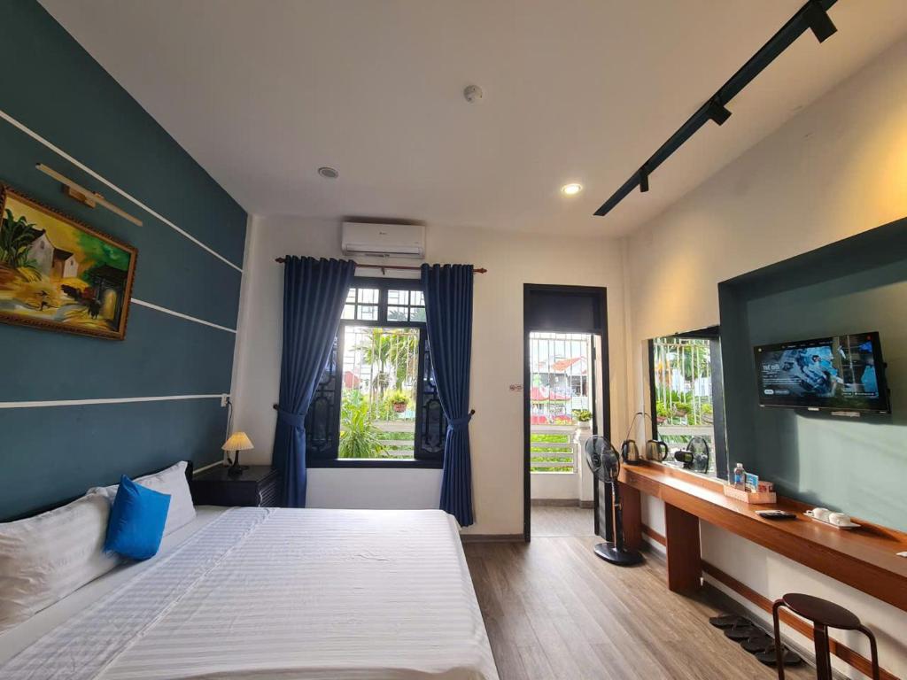 a bedroom with a bed and a desk and window at SUN HOTEL in Hue