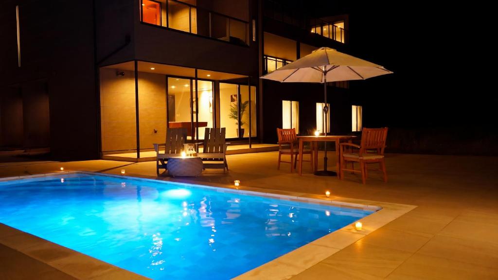 a swimming pool with a table and an umbrella at CIN Garden Terrace in Futtsu
