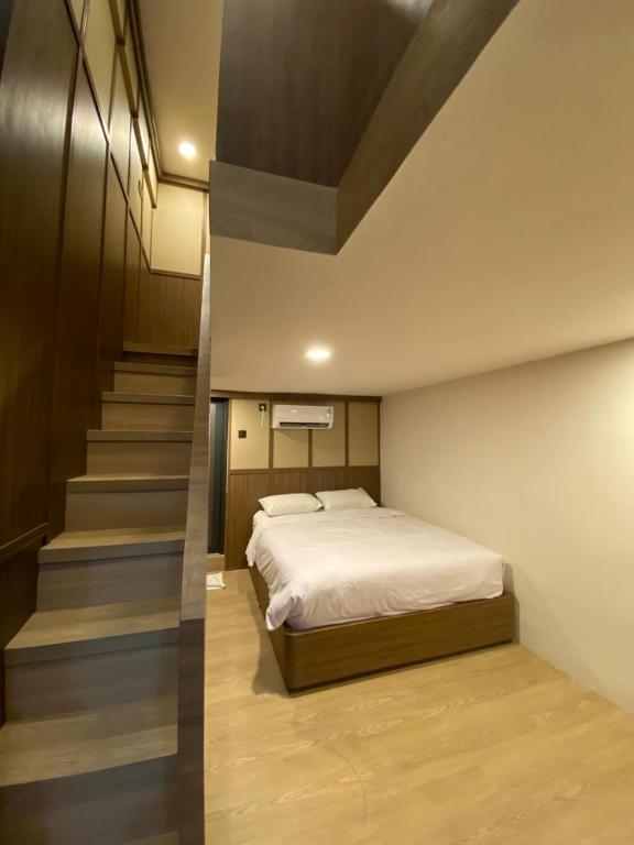 a bedroom with a bed and a staircase at INSAHAUS Guest House in Kotalama