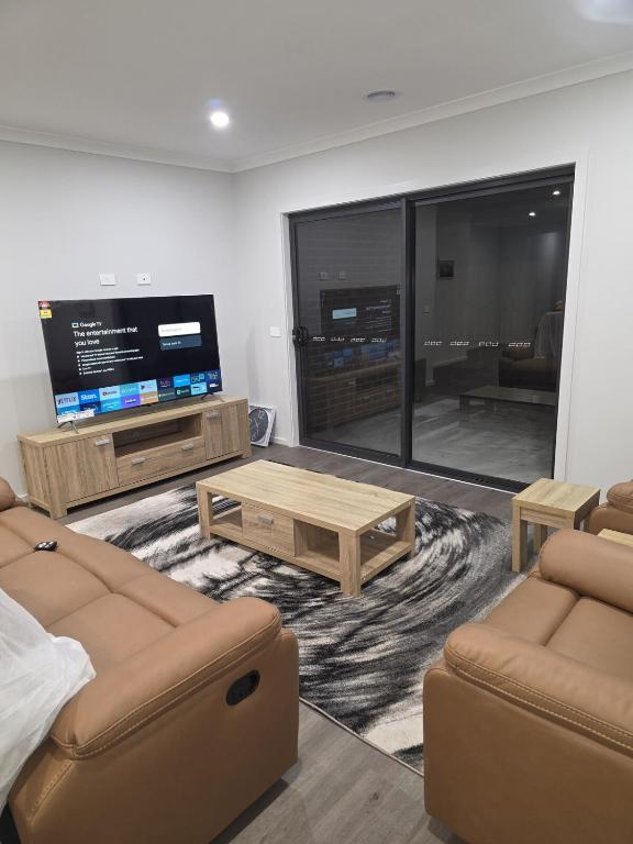 a living room with couches and a flat screen tv at 11 Lomond street in Beveridge