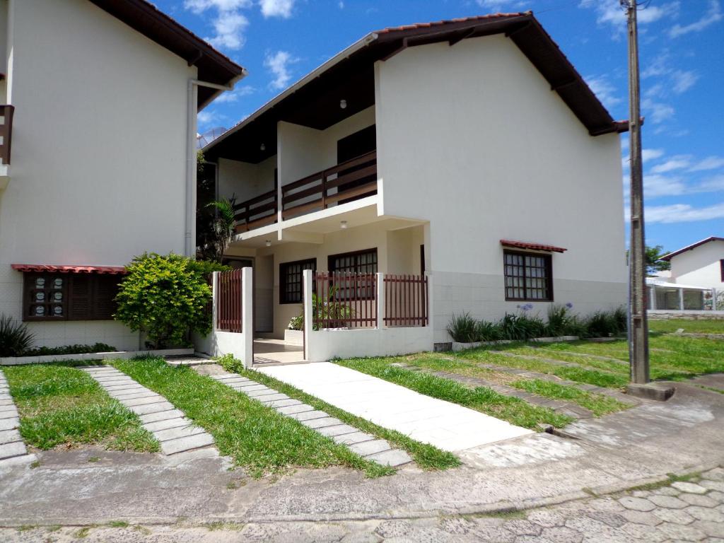 a white house with a pathway in front of it at RESIDENCIAL COM CASAS DE 2 DORM - Praia Garopaba in Garopaba