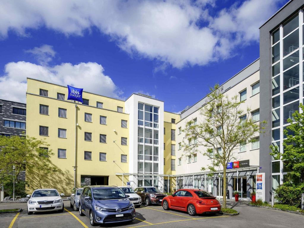 a parking lot with cars parked in front of a building at ibis budget Winterthur in Winterthur