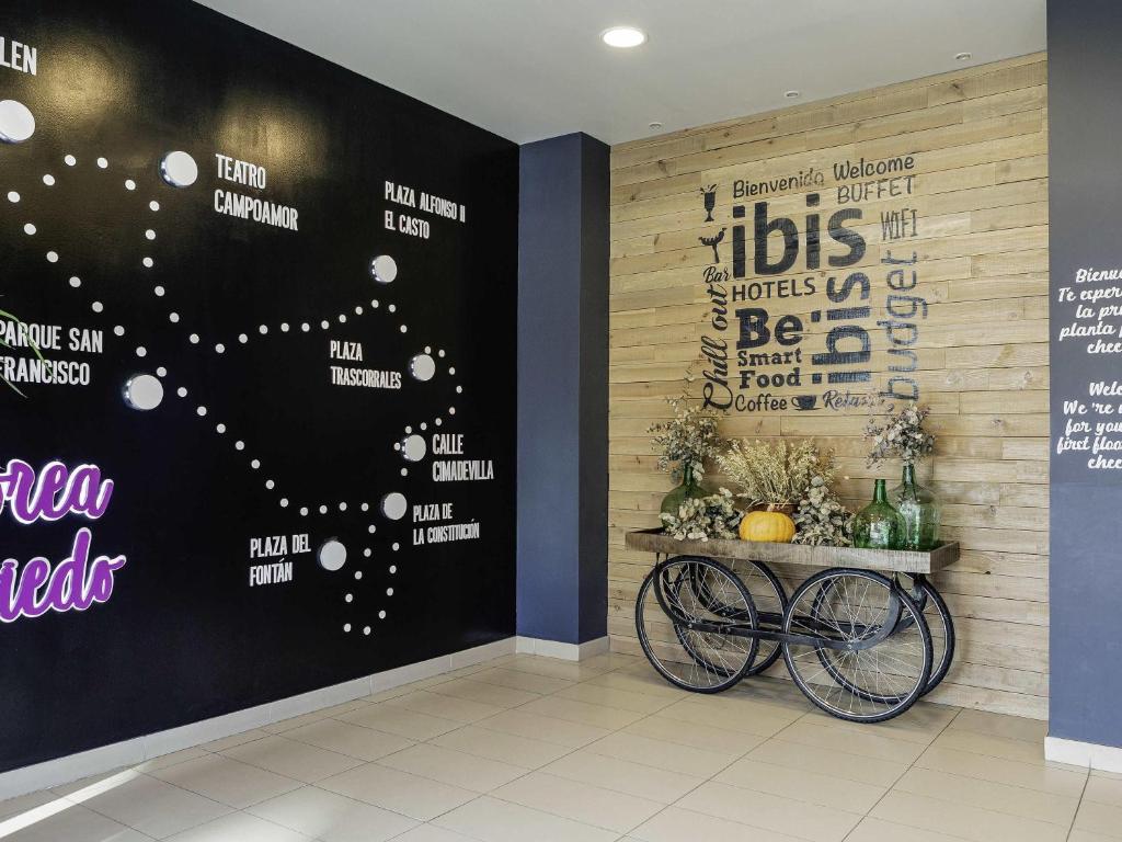 a room with a wall with a sign and a table at Ibis Budget Oviedo in Oviedo