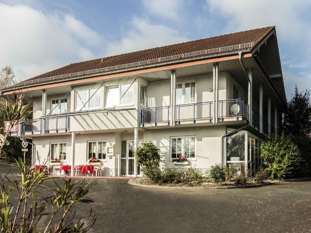 ein großes weißes Haus mit Balkon und Tischen in der Unterkunft ibis Kassel Melsungen in Melsungen