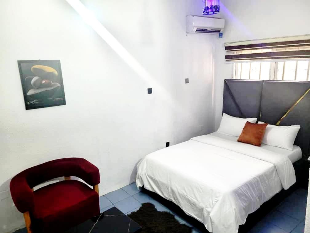 a bedroom with a bed and a red chair at G Spot Hotel in Port Harcourt