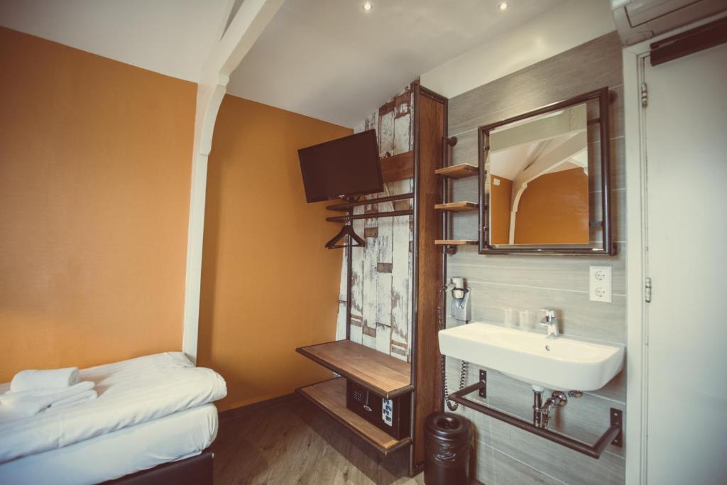 a bathroom with a sink and a mirror and a bed at Budget Hotel Tourist Inn in Amsterdam
