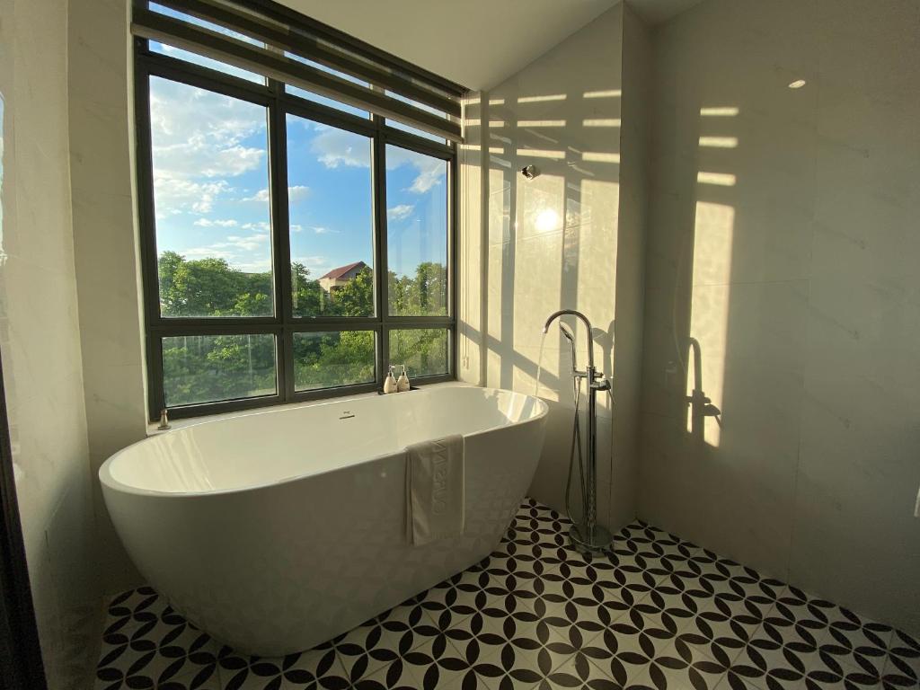 a large bath tub in a bathroom with a window at Moma Paris Hotel Ninh Bình in Ninh Binh