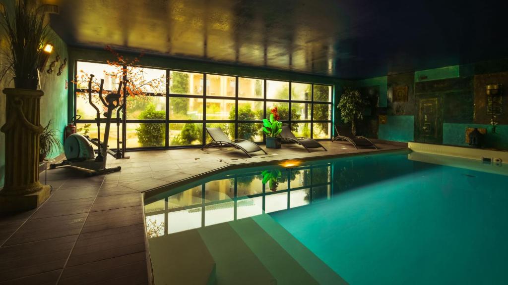 a large swimming pool in a house with a large window at The Originals City, Hôtel Le Village Provençal, Aix-en-Provence Nord (Inter-Hotel) in Pertuis