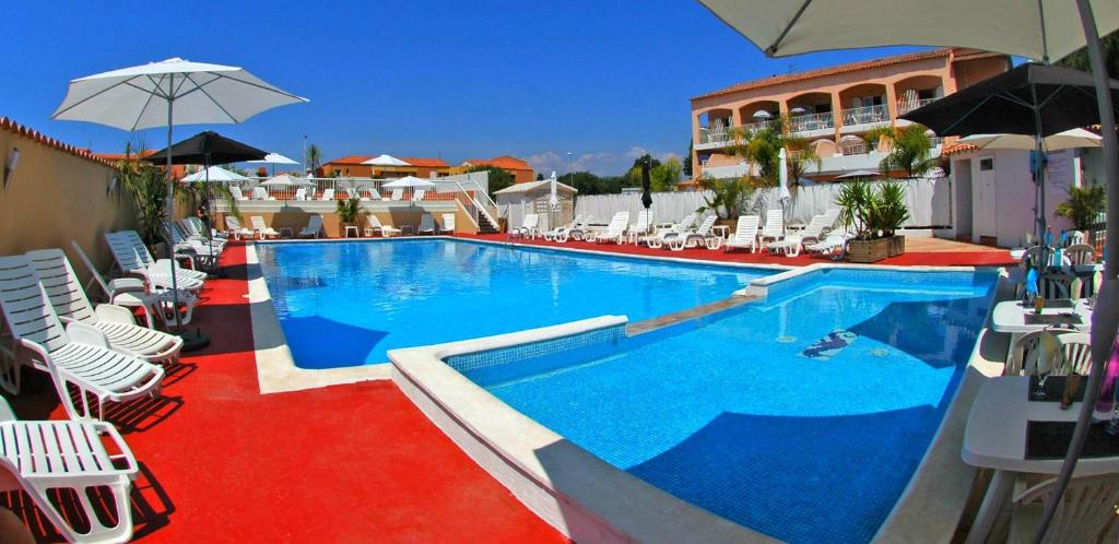 una gran piscina con sillas y sombrillas blancas en Argentiere-Club, en La Londe-les-Maures
