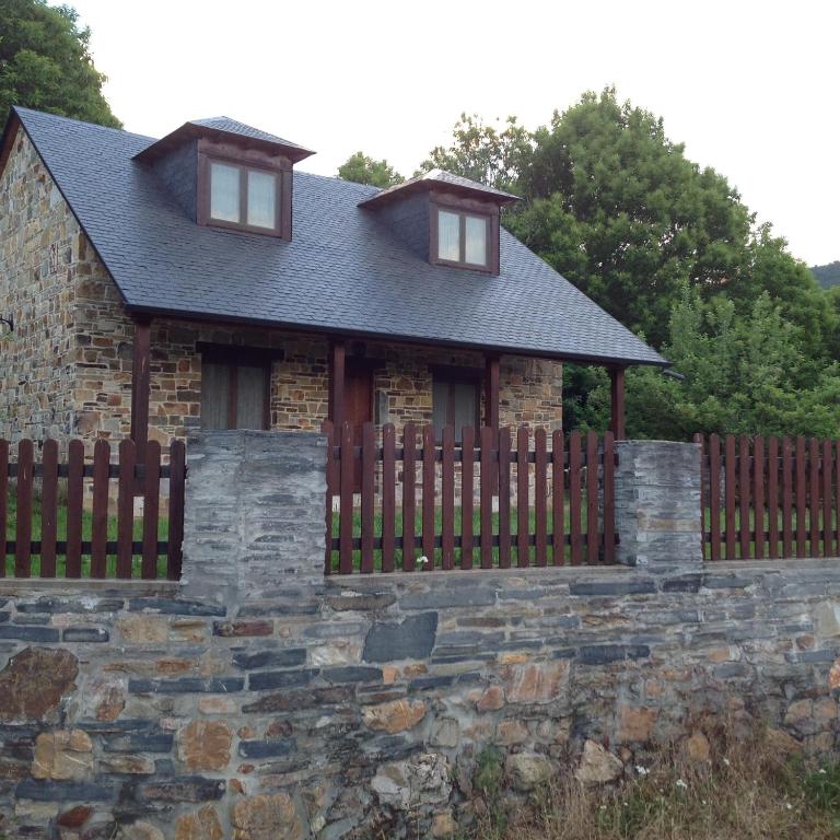 a house with a wooden fence and a stone wall at El Mirador de los Trobos in Villar de Otero