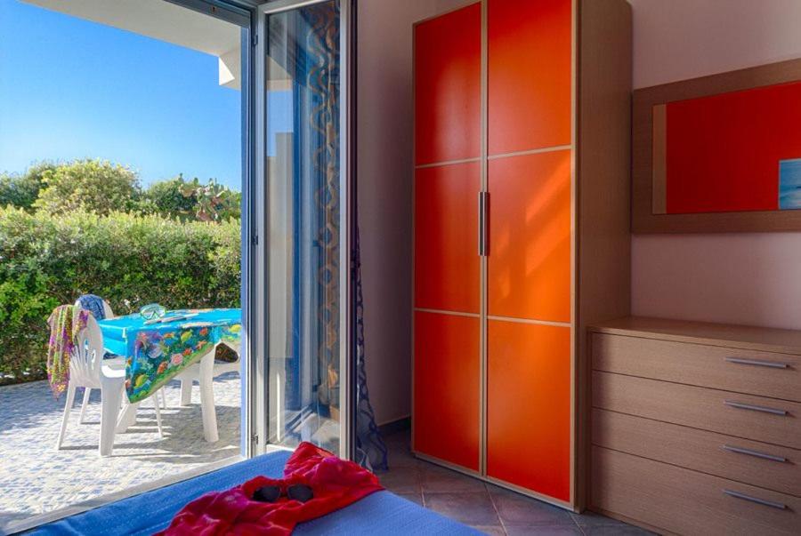 カーポ・ドルランドにあるResidence Mare Bluのベッドルーム1室(オレンジ色のクローゼット、テーブル、椅子付)