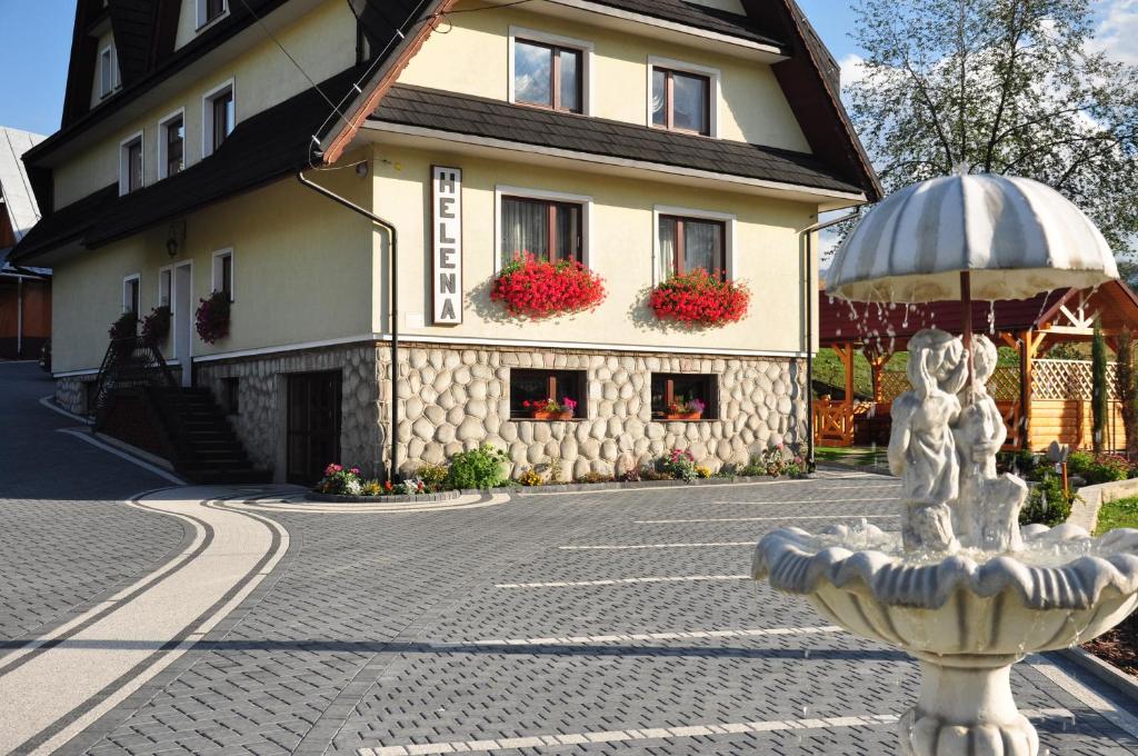 a house with a fountain in front of a building at Willa Helena in Poronin